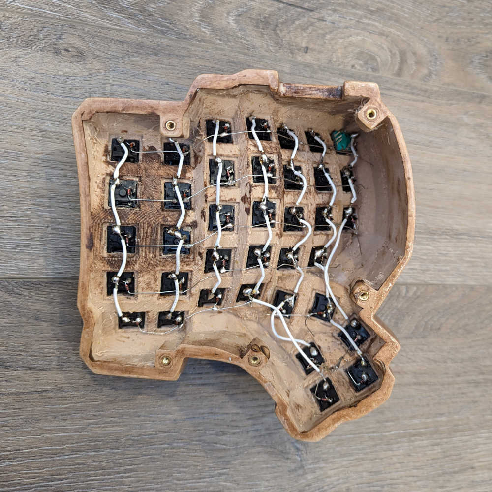 A keyboard half with wires soldered to the switches to form columns of the keyboard matrix
