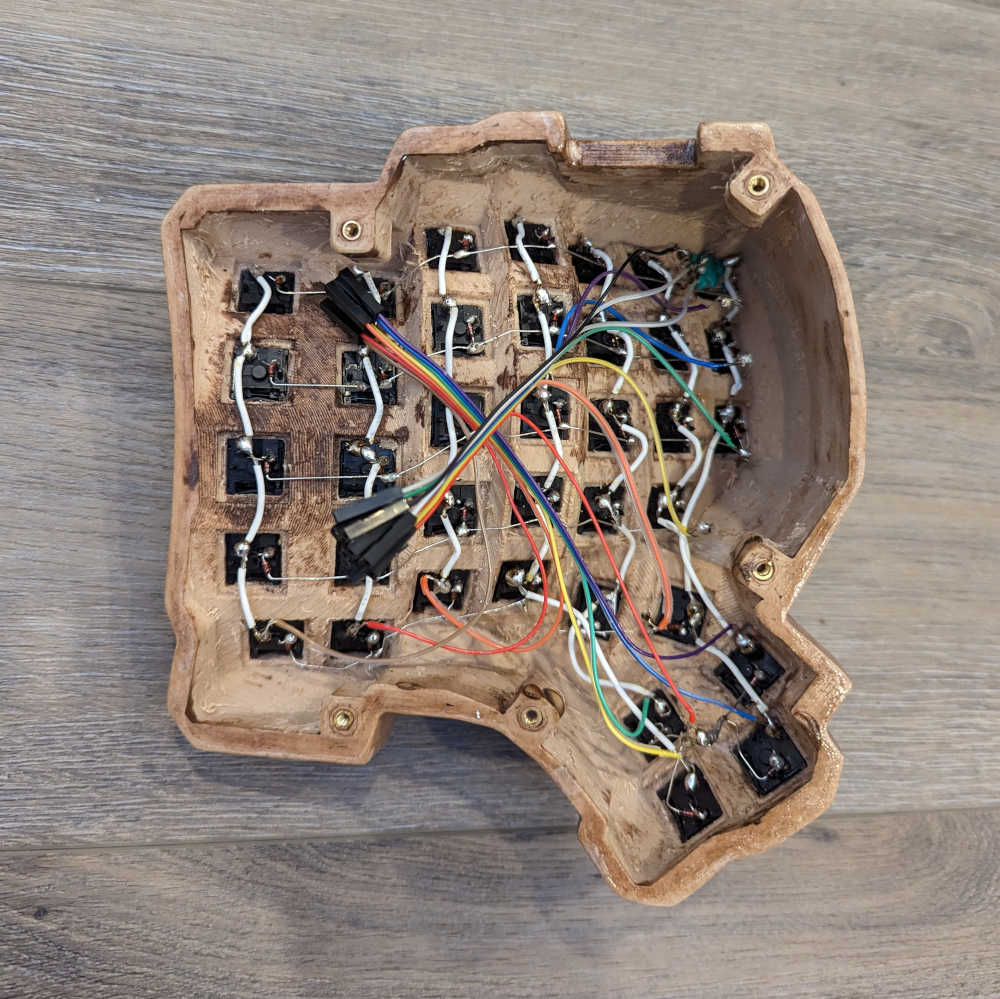 A keyboard half with DuPont connectors installed to each row and column of the keyboard matrix